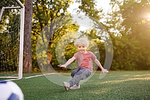 Little boy having fun playing a soccer/football game on summer day. Active outdoors game/sport for children