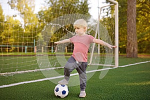 Little boy having fun playing a soccer/football game on summer day. Active outdoors game/sport for children