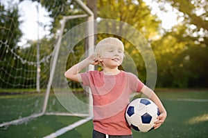 Little boy having fun playing a soccer/football game on summer day. Active outdoors game/sport for children