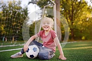 Little boy having fun playing a soccer/football game on summer day. Active outdoors game/sport for children