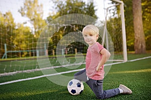 Little boy having fun playing a soccer/football game on summer day. Active outdoors game/sport for children