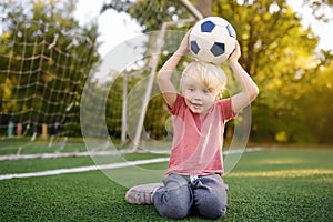 Little boy having fun playing a soccer/football game on summer day. Active outdoors game/sport for children