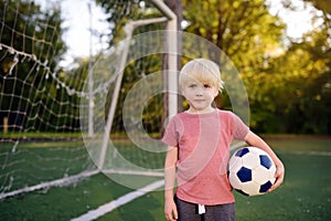 Little boy having fun playing a soccer/football game on summer day. Active outdoors game/sport for children