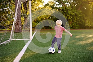 Little boy having fun playing a soccer/football game on summer day. Active outdoors game/sport for children