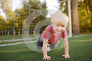 Little boy having fun playing a soccer/football game on summer day. Active outdoors game/sport for children