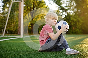 Little boy having fun playing a soccer/football game on summer day. Active outdoors game/sport for children