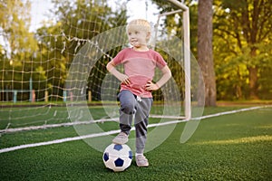 Little boy having fun playing a soccer/football game on summer day. Active outdoors game/sport for children