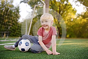 Little boy having fun playing a soccer/football game on summer day. Active outdoors game/sport for children