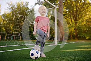 Little boy having fun playing a soccer/football game on summer day. Active outdoors game/sport for children