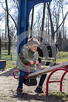 Little boy having fun on swing on playground. Happy child enjoy swinging. Active outdoors leisure