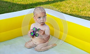 A little boy is having fun with toys in an inflatable yellow pool.