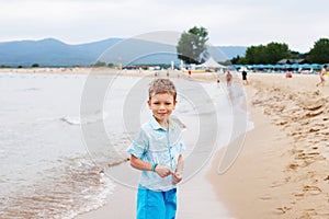 Little boy having fun on tropical ocean beach. Kid during family sea vacation. Summer water fun.