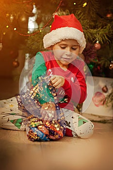 Little boy having fun under a christmas tree dressed in festive pajama and hood