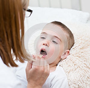 Little boy having his throat examined by health professional