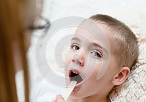 Little boy having his throat examined by health professional