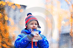 Little boy having hot drink in cold city winter