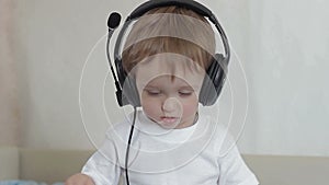 Little boy with headphones shakes his head and waves his arms
