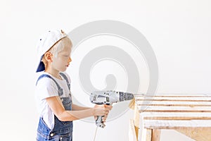 Little boy in a helmet plays in the builder with tools.  over white