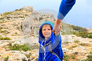 Little boy helped by parent on hiking in mountains