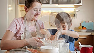 Little boy helping his mother making dough and mixing it with hands. Children cooking with parents, little chef, family
