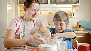 Little boy helping his mother making dough and mixing it with hands. Children cooking with parents, little chef, family