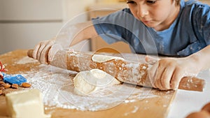 Little boy helping mother and rolling dough on wooden board. Children cooking with parents, little chef, family having