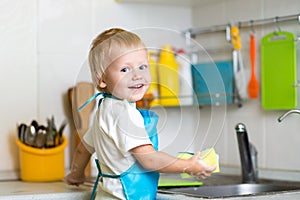 Little boy helping mother washing dishes in the kitchen
