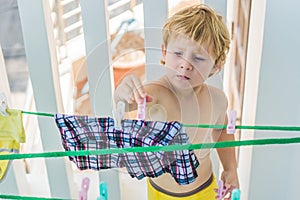 A little boy helps her mother to hang up clothes