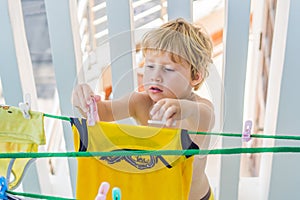 A little boy helps her mother to hang up clothes