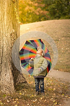 Little boy hiding behind colorful umbrella outdoors