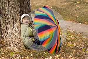 Little boy hiding behind colorful umbrella outdoors