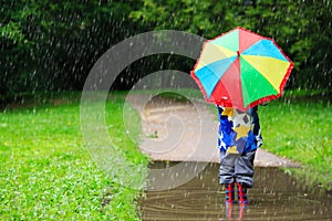 Little boy hiding behind colorful umbrella outdoors