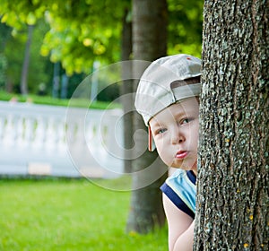 Little boy hiding behind tree