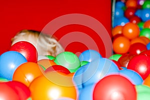 Little boy hiding behind two plastic balls