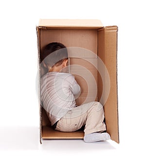 Little boy hiding in cardboard box