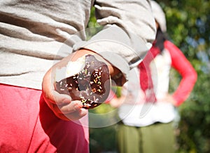 little boy hiding a chocolate donut.