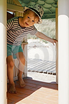 The little boy is hiding in a small plastic playhouse