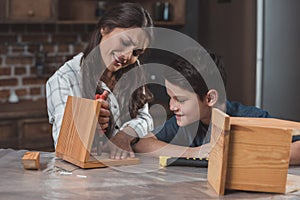Little boy  and his beautiful mother crafting a wooden birdhouse