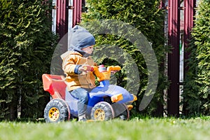 Little boy on his bike on green lawn backyard