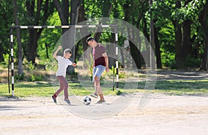 Little boy with his dad playing football on soccer pitch