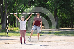 Little boy with his dad playing football on soccer pitch