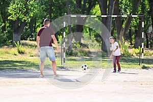 Little boy with his dad playing football on soccer pitch