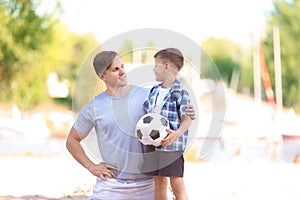 Little boy and his dad with soccer ball outdoors