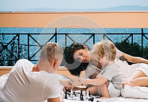 Little boy and his father with mother playing chess