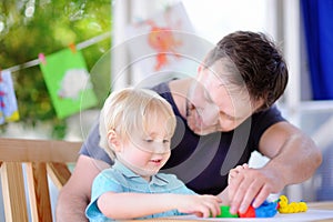 Little boy with his father playing with colorful modeling clay