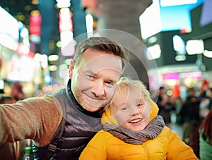 Little boy and his father taking selfie on Times Square in evening, downtown Manhattan photo