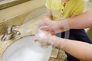 Little boy and his father washing their hands with soap in bathroom together. Hygiene for little child