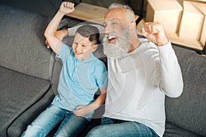 Little boy and his grandfather celebrating victory of favorite team