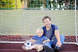 Little boy and his middle age father having fun playing a soccer/football game on summer day