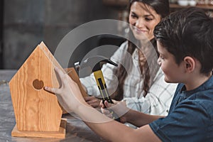 Little boy and his mother building a wooden birdhouse